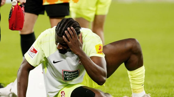 Ragnar Ache fasst sich an den Kopf nachdem er von einem geworfenen Gegenstand getroffen wurde. - &copy; Roland Weihrauch/dpa/Archivbild