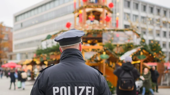 Ein Polizist steht auf einem Weihnachtsmarkt. - &copy; Julian Stratenschulte/dpa/Symbolbild