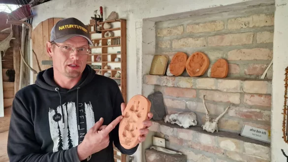 Wildnisp&auml;dagoge Paul Wernicke zeigt in seiner Wildnisschule in Bad Belzig den Pfotenabdruck eines Wolfes in Ton. - &copy; Cevin Dettlaff/dpa-Zentralbild/dpa