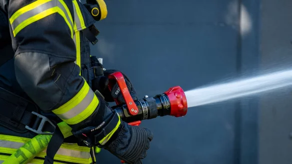 Ein Mitglied der Feuerwehr spritzt aus einem Schlauch mit Wasser. - &copy; David Inderlied/dpa/Symbolbild