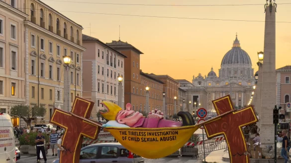 Einer Figur des Künstlers Jacques Tilly, die ironisch die Kirche für ihre Missbrauchsermittlungen kritisiert, steht in Rom in Sichtweite des Petersdoms. - © Ricarda Hinz/dpa