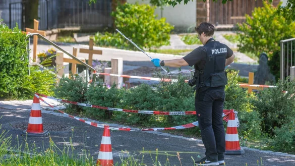 Eine Mitarbeiterin der Spurensicherung vermisst Spuren am Tatort auf einem Friedhof. - &copy; Christoph Schmidt/dpa