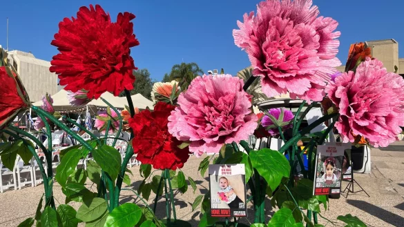 Blumen mit Bildern von Kindern, die seit dem Massaker der Hamas im israelischen Grenzgebiet am 07. Oktober als Geiseln gehalten und vermisst werden, stehen vor dem Kunstmuseum in Tel Aviv. - &copy; Sara Lemel/dpa