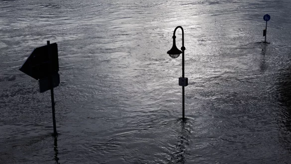 Blick auf Verkehrsschilder und eine Stra&szlig;enlaterne am &uuml;berfluteten Weserufer. - &copy; Friso Gentsch/dpa