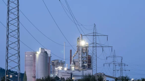 Strommasten stehen im Morgenlicht vor einem Zementwerk: Die Bundesregierung will den Strompreis f&uuml;r die Wirtschaft durch eine Steuerreform dr&uuml;cken senken. - &copy; Silas Stein/dpa