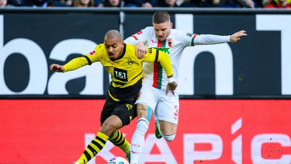 Dortmunds Donyell Malen (l) versucht den Ball vor Augsburgs Mads Pedersen (r) zu behaupten. - &copy; Tom Weller/dpa