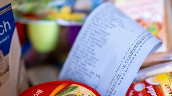 Ein Kassenbon im Einkaufskorb: Die Menschen in Deutschland fürchten sich einer Umfrage zufolge vor steigenden Lebenshaltungskosten. - © Monika Skolimowska/dpa