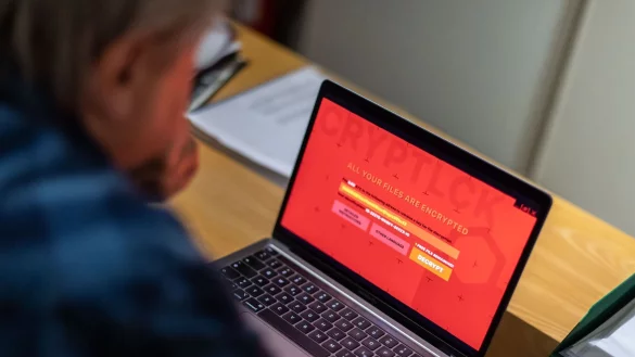 Ein Mann sitzt vor einem Laptop, der mit einem Verschlüsselungstrojaner (Ransomware) befallen ist. - © Lino Mirgeler/dpa