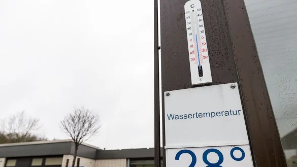 Ein Schild mit der aktuellen Wassertemperatur von 28 Grad h&auml;ngt unter einem Thermostat. - &copy; picture alliance / Guido Kirchner/dpa