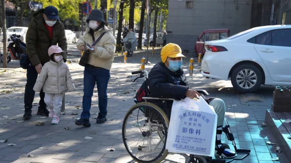Ein Junge in einem Rollstuhl h&auml;lt in Peking eine Tasche aus der radiologischen Abteilung eines Kinderkrankenhauses. In den vergangenen Tagen hatten Berichte &uuml;ber die starke H&auml;ufung von Atemwegserkrankungen bei Kindern Sorgen aufkommen lassen. - &copy; Ng Han Guan/AP/dpa