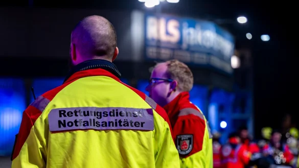 Sanit&auml;ter stehen vor dem Stadion bei einem Einsatz, w&auml;hrend im Hintergrund ein Verletzter versorgt wird. - &copy; David Inderlied/dpa