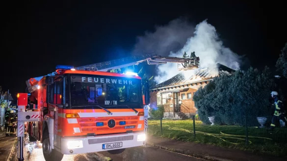 Feuerwehrleute sind &uuml;ber eine Drehleiter an einem brennenden Haus im Einsatz. - &copy; Vincent Kempf/dpa