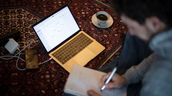 Ein Mann sitzt im Homeoffice mit Laptop auf dem Teppich und arbeitet. - © Sina Schuldt/dpa/Illustration