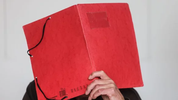 Der Angeklagte im &laquo;Cold Case&raquo; h&auml;lt sich im Gerichtssaal eine Mappe vor das Gesicht. - &copy; Oliver Berg/dpa