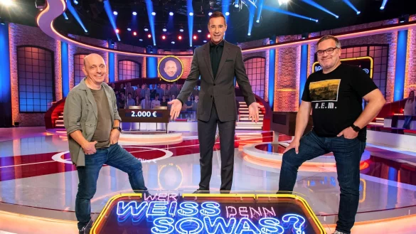 Moderator Kai Pflaume (M) neben Bernhard Hoëcker (l) und Elton: Die beiden Teamkapitäne werden bei «Wer weiß denn sowas?» 25 Stunden ohne Pause versuchen, die richtigen Antworten auf Quizfragen zu finden. - © Morris Mac Matzen/ARD /dpa