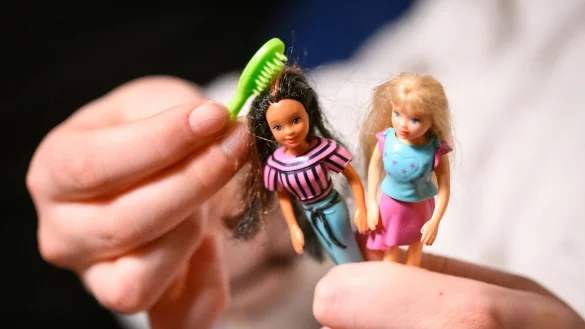Eine junge Frau k&auml;mmt die Haare von zwei der gr&ouml;&szlig;eren Polly Pocket Puppen. - &copy; Jonas Walzberg/dpa