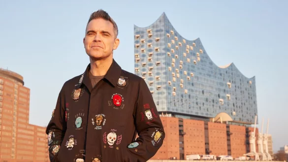Robbie Williams auf einer Barkasse im Hamburger Hafen. Im Hintergrund ist die Elbphilharmonie zu sehen. - &copy; Georg Wendt/dpa