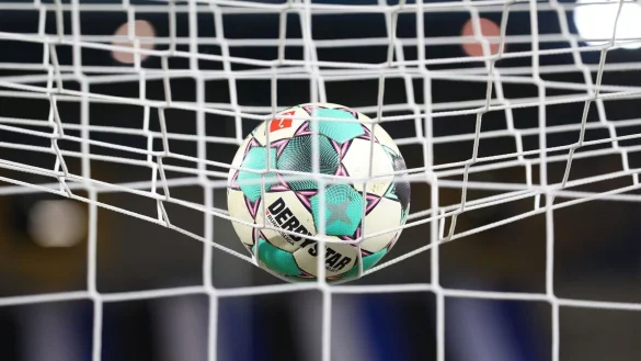 Ein Fußball liegt vor der Partie im Netz. - © Friso Gentsch/dpa/Symbolbild