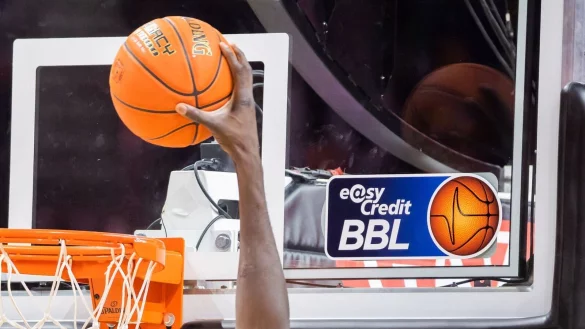 Ein Spieler dunkt, wobei das Logo der Basketball-Bundesliga BBL zu sehen ist. - © Christoph Soeder/dpa
