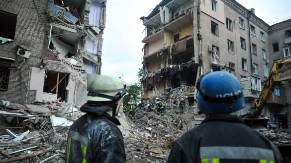 Rettungskr&auml;fte im ukrainischen Saporischschja schauen auf die Tr&uuml;mmer eines zerst&ouml;rten Wohnhauses. - &copy; Ukrinform/dpa