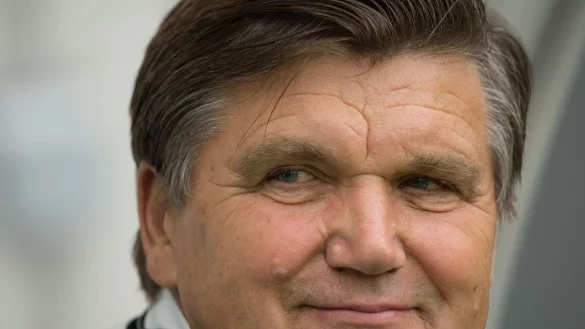 Der ehemalige Fußballtrainer Hans Meyer lächelt im Stadion. - © picture alliance / dpa/Archivbild