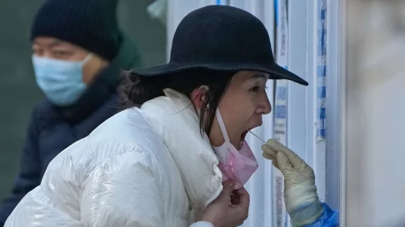 Eine Frau unterzieht sich in einer Coronavirus-Teststelle in Peking einem routinem&auml;&szlig;igen COVID-19-Rachenabstrich. - &copy; Andy Wong/AP/dpa