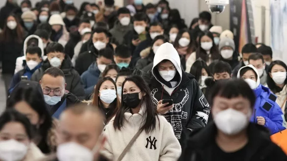 Menschen mit Mund-Nasen-Schutz gehen während der Hauptverkehrszeit durch eine U-Bahn-Station in Peking. - © Uncredited/kyodo/dpa