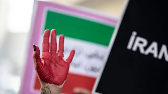 Eine rot bemalte Hand einer Demonstrantin erhebt sich zwischen Plakaten w&auml;hrend einer Demonstration vor dem iranischen Konsulat in Istanbul. - &copy; Onur Dogman/SOPA/ZUMA/dpa