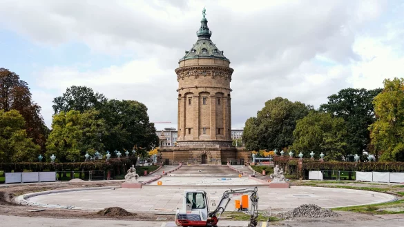 Ein Bagger steht vor der trockengelegten Fontänenanlage von Mannheims Wasserturm. - © Uwe Anspach/dpa