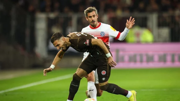 St. Paulis Leart Paqarada (l) und Kiels Fin Bartels im Kampf um den Ballbesitz. - &copy; Christian Charisius/dpa