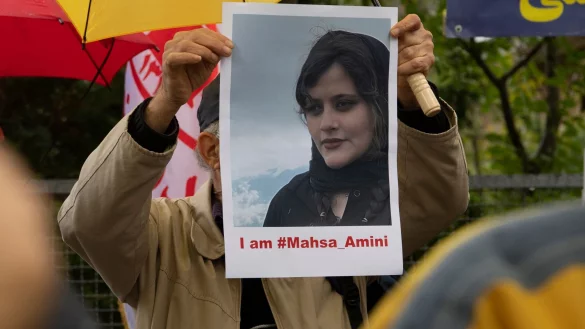 Bei einem Protest in Berlin h&auml;lt ein Mann ein Bild der verstorbenen Mahsa Amini in H&auml;nden. - &copy; Paul Zinken/dpa
