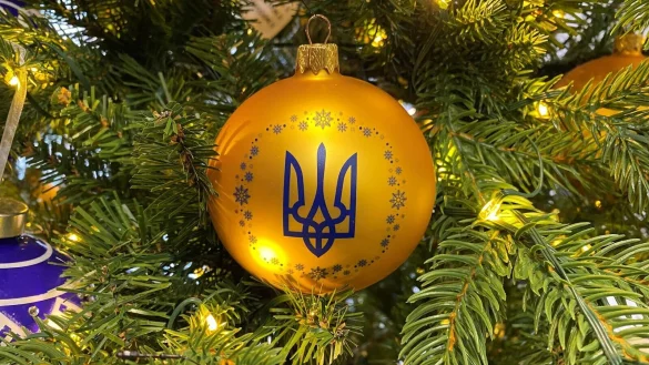 An einem geschm&uuml;ckten Baum h&auml;ngt eine Kugel in den ukrainischen Nationalfarben und dem Dreizack als Wappen. - &copy; Ulf Mauder/dpa