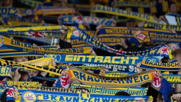 Fans von Eintracht Braunschweig stehen mit ihren Schals auf der Trib&uuml;ne. - &copy; Swen Pf&ouml;rtner/dpa/Archivbild