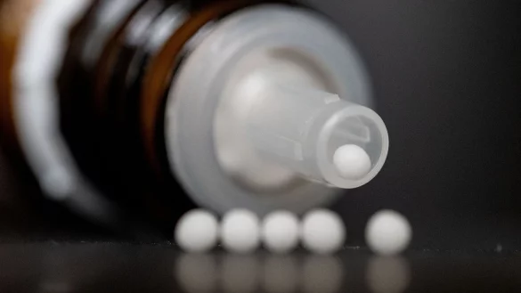 Hom&ouml;opathische Kugeln liegen vor einer Spenderflasche auf einem Tisch. - &copy; Marijan Murat/dpa
