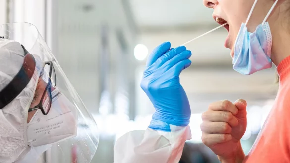 Ein medizinischer Mitarbeiter entnimmt einer Frau einen Abstrich f&uuml;r einen Corona-Test. - &copy; Moritz Frankenberg/dpa/Symbolbild