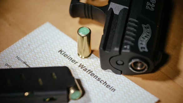Ein Kleiner Waffenschein liegt zwischen einer Schreckschuss-Pistole, einem Magazin und einer Patrone. - &copy; Oliver Killig/ZB/dpa/Illustration