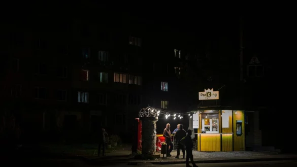 Menschen stehen an einer Stra&szlig;e vor einer beleuchteten Bar. In der Ukraine greift Russland weiter gezielt Kraftwerke und andere Infrastruktur an. - &copy; Emilio Morenatti/AP/dpa