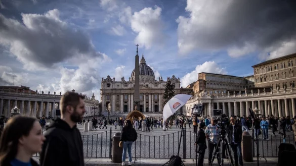 Touristen, Gläubige und Journalisten stehen vor dem Petersdom in der Vatikanstadt. - © Oliver Weiken/dpa