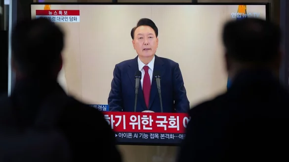 Menschen schauen auf einen Fernsehbildschirm, der die im Fernsehen &uuml;bertragene Ansprache des s&uuml;dkoreanischen Pr&auml;sidenten Yoon Suk Yeol an einem Busbahnhof zeigt. Ein zweiter Amtsenthebungsantrag gegen Yoon hat die ben&ouml;tigte Zweidrittelmehrheit in der Nationalversammlung erreicht. (Archivbild) - &copy; Lee Jin-man/AP/dpa