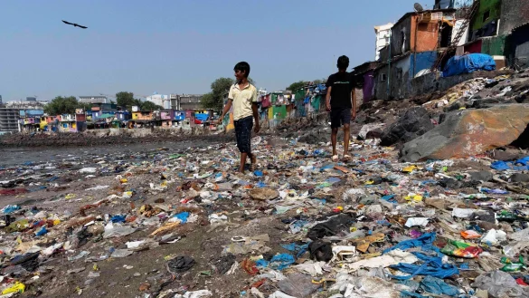 Menschen spazieren am Strand des Badhwar Park im indischen Mumbai an Plastikm&uuml;ll vorbei. (Archivbild) - &copy; Rajanish Kakade/AP/dpa