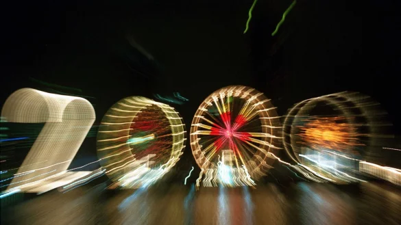 25 Jahre alt ist dieses «2000»-Foto: Ein Zoom-Effekt verfremdet eine große «2» und drei Riesenräder am Mainufer in Frankfurt in der Silvesternacht 1999/2000. - © Arne Dedert/dpa