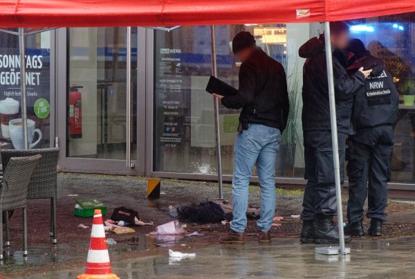Polizeibeamte untersuchen unter einem Zeltdach den Tatort in der Innenstadt. - © Henning Kaiser/dpa