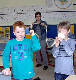 Hörübung: Till und Fynn reden ins und horchen am Schlauchtelefon. Im Hintergrund hält Lehrerin Karin Wiebesiek den Schlauch. Die Schüler nehmen an der Projektwoche „Wir wollen leise Schule werden" der Grundschule Nord teil. - © Dohna