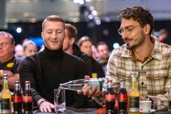 Fußballspieler Mats Hummels (r) schüttet seinem Teamkollegen Marco Reus ein Glas Wasser ein. - © David Inderlied/dpa/Archivbild