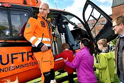 Bitte einsteigen: Eine Mutter hebt ihr Kind ins Hubschrauber-Cockpit. Der Mitarbeiter der Luftrettung h&auml;lt nach Wartenden Ausschau. - &copy; Barbara Franke