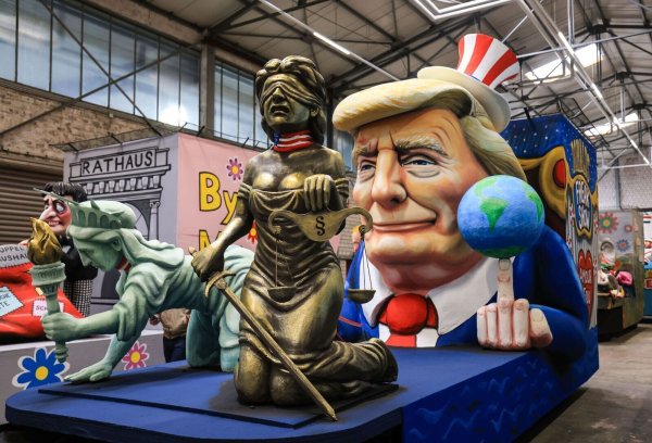 Einer der Wagen im Kölner Rosenmontagszug zeigt US-Präsident Donald Trump, der sich die Freiheitsstatue und die Justitia - Demokratie und Rechtsstaat - unterworfen hat. (Archivbild) - © Oliver Berg/dpa