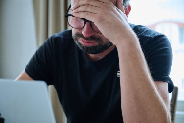 Ein Mann sitzt vor einem Laptop und seufzt. - © Annette Riedl/dpa
