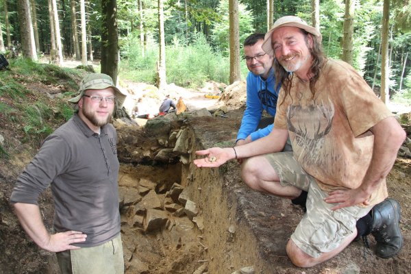 Funde im Wald: (von links) Johannes Müller-Kissing mit den Experten der Cardiff University, Dr. Oliver Davis und Ian Dennis, Dozent für Grabungstechnik und Fundbearbeitung. Sie zeigen den Spinnwirtel, der auf der Fläche gefunden wurde. - © Marlen Grote