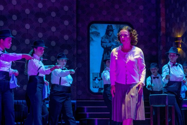 „Der fliegende Holländer": Susanne Serfling als Senta und Mitglieder des Chores in einer Spielszene. Im Hintergrund: Derrick Ballard in der Rolle des „Holländers". ? - © Foto: Landestheater/Kerstin Schomburg