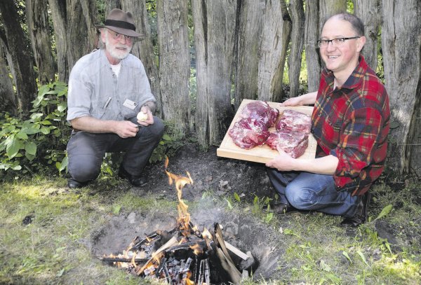 Feuriger Auftakt: Einige Basaltsteine werden durch Harry Meyer (links) und Karl Banghard in einem Holzfeuer erhitzt. Auf den glühenden Steinen brät das Fleisch und das Gemüse dann unter der Erde. - © Horst Biere